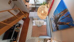 A modern interior with a staircase, a sofa set, a dining area, and a large painting.