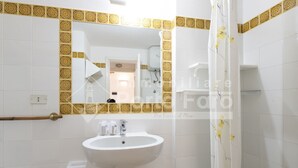A bathroom with a white sink, a mirror with a decorative border, and a shower curtain with a floral pattern.