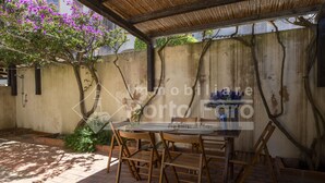 An outdoor patio with a table and chairs, a pergola, and a wall with climbing plants.