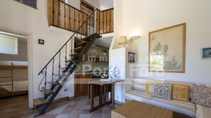 A spacious living area with a staircase, a sofa set, and a dining table.