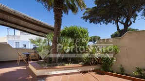 A patio with a tiled floor, a pergola, and a variety of plants.