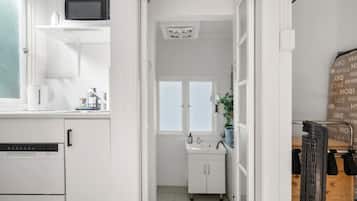 A narrow kitchen with white cabinets, a microwave, and a sink.
