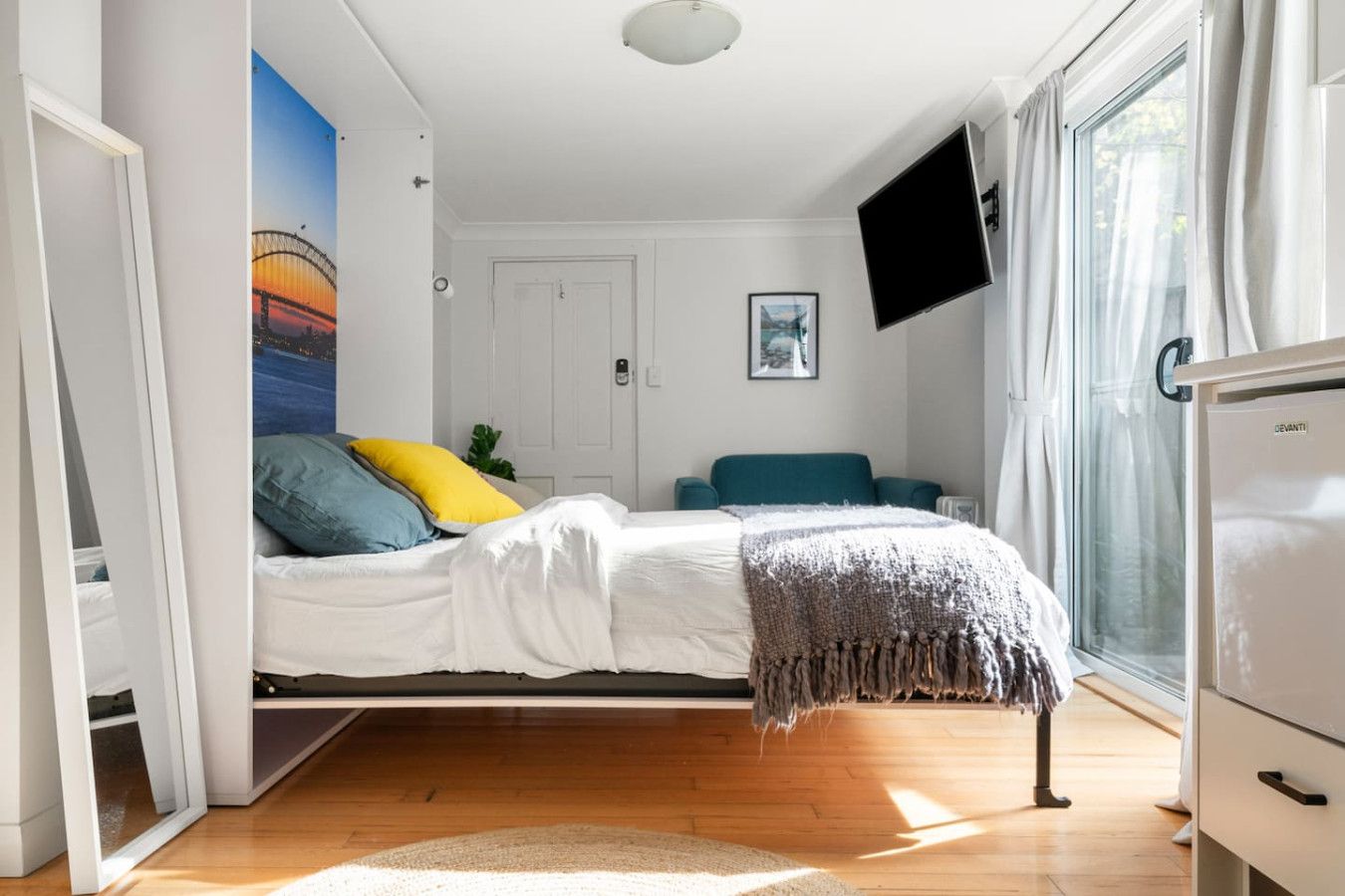 A bedroom with a bed, a TV, a window, and a door.