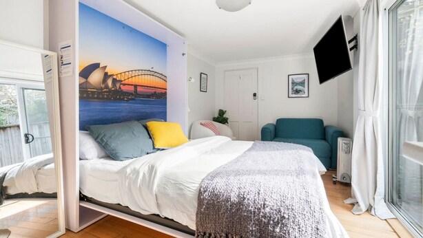 Una camera da letto con un letto, una TV a parete, un divano e un'ampia finestra.