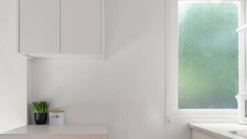 A compact kitchen with white cabinets, a built-in refrigerator, and a window with a view of greenery.