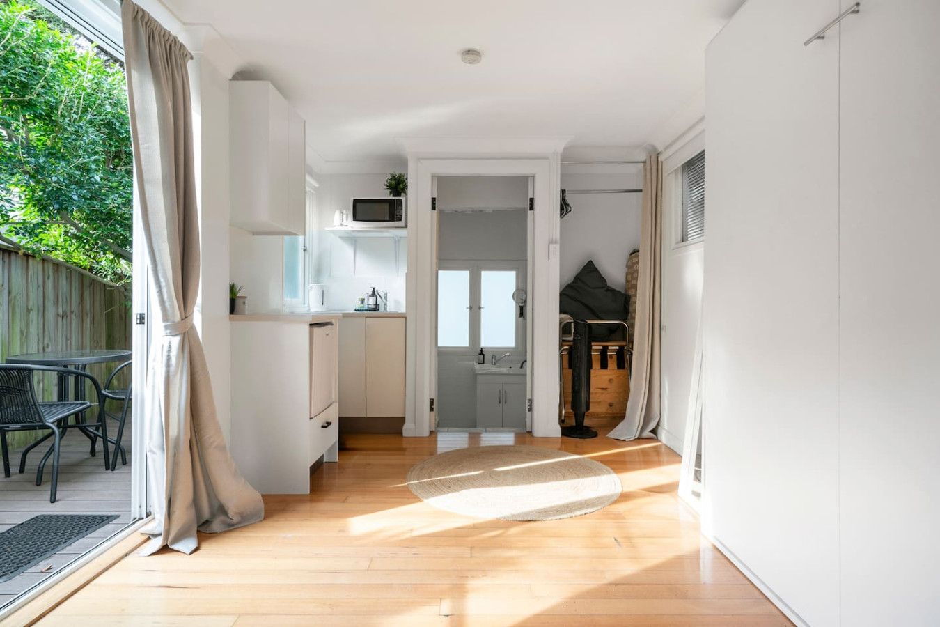 A modern kitchen with white cabinets, a microwave, and a small window.