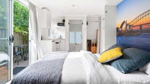 Una moderna camera d'hotel con un letto grande, vista sull'Opera di Sydney e un angolo cottura.