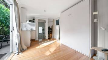 Un intérieur moderne et bien éclairé, avec un plancher en bois, un coin repas comprenant une table et des chaises, et une cuisine dotée de meubles blancs.