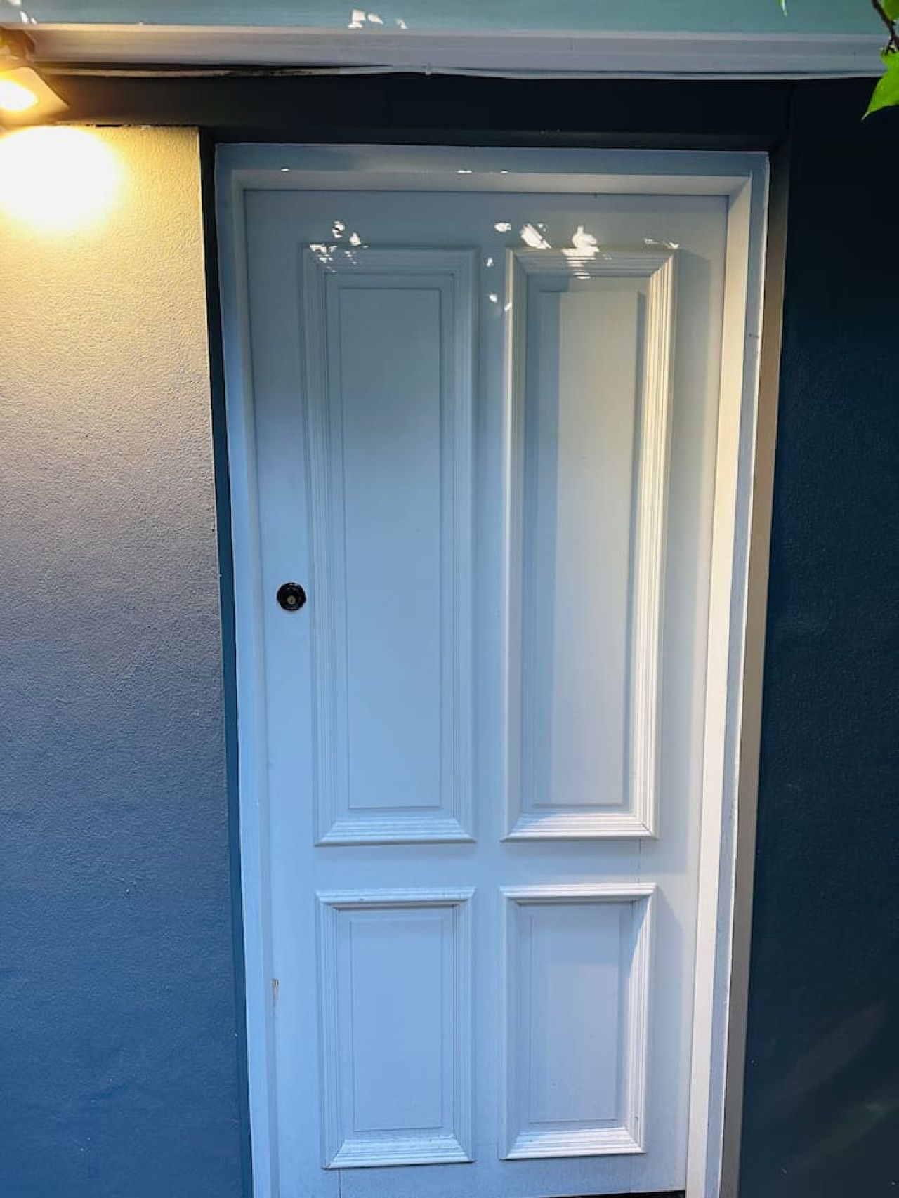 A white door with a keyhole, set in a dark-colored wall.