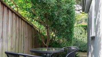 Un patio con pavimento in legno, un tavolo rotondo e quattro sedie.