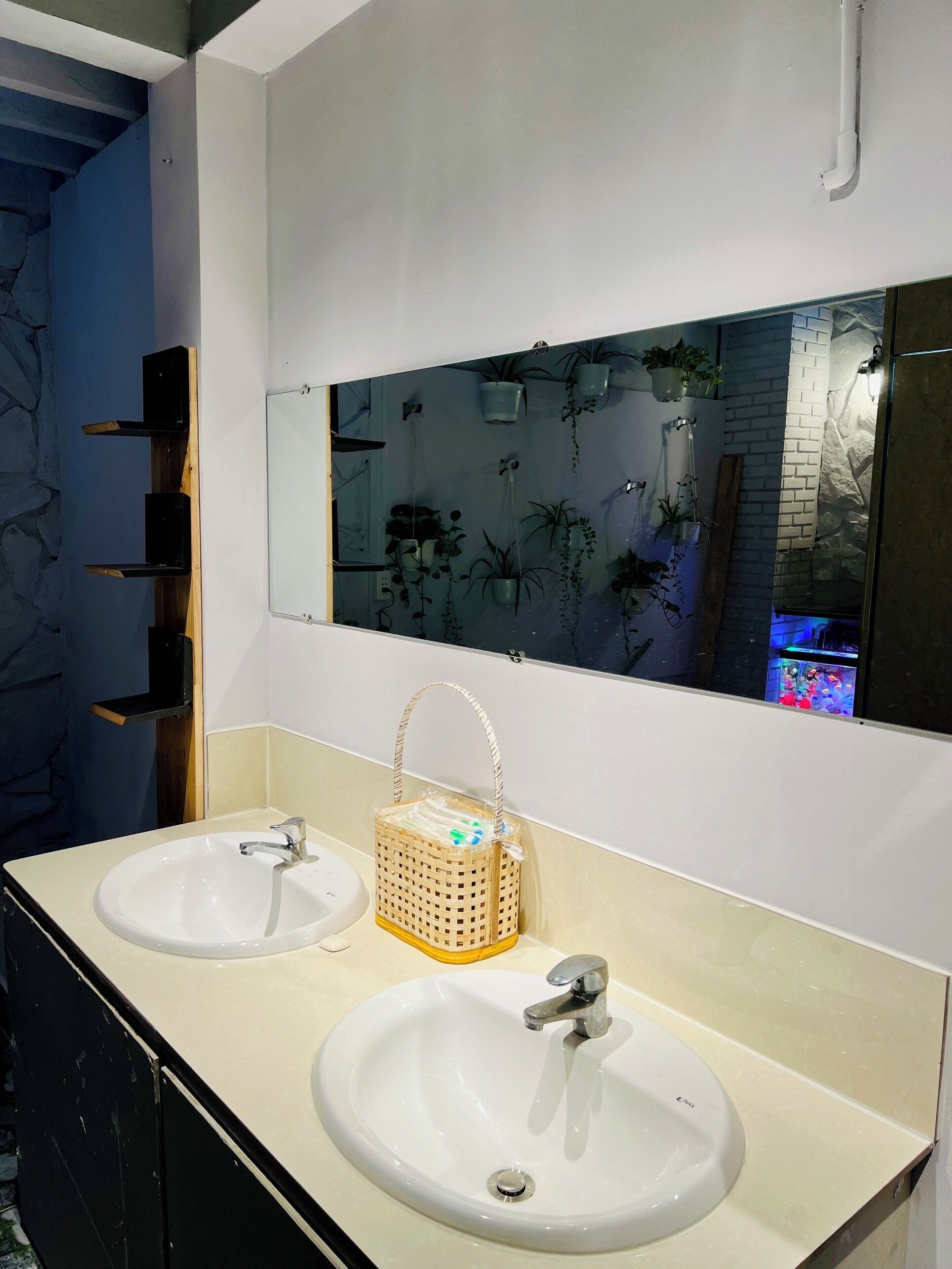 Un baño con dos lavamanos, un espejo y una cesta colgante.