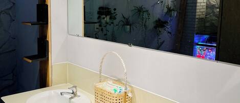 Un baño con dos lavamanos, un espejo y una cesta colgante.