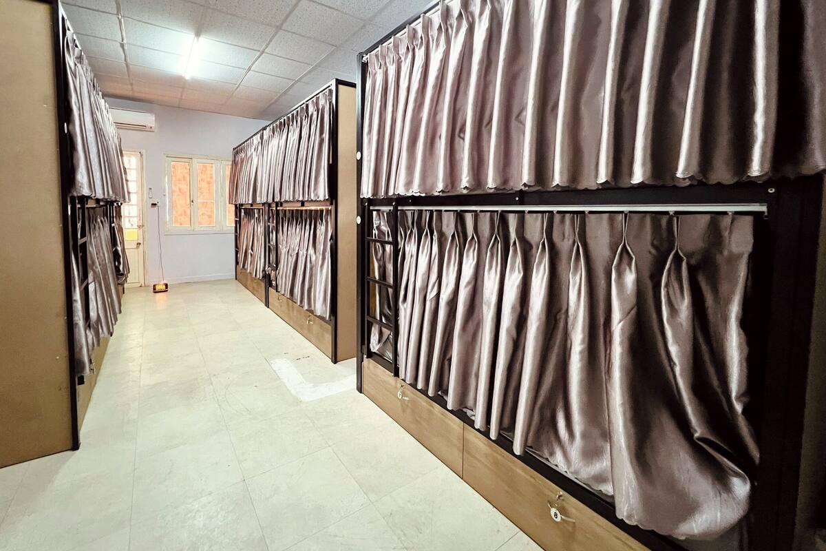 A hotel corridor with rows of rooms, each with a curtain divider and a door.