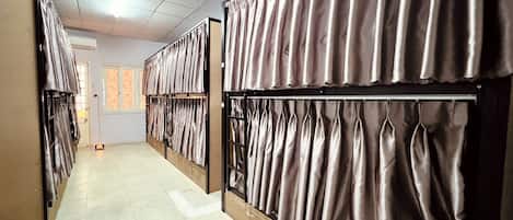 A hotel corridor with rows of rooms, each with a curtain divider and a door.