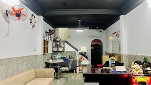 A modern living room with a sofa, a dining table, and a kitchen area with cabinets and a sink. - AULE HOSTEL (Ho Chi Minh City)