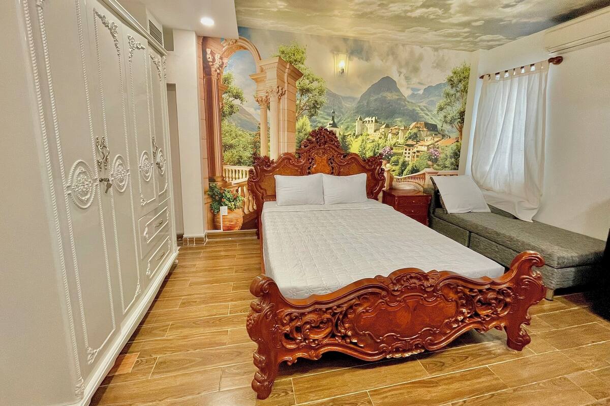 A bedroom with a large bed, a wardrobe, and a mural of a mountainous landscape.