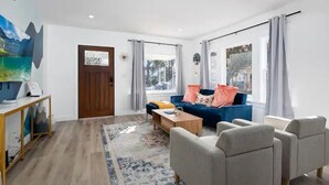 A modern living room with a sofa, armchairs, a coffee table, and a rug.