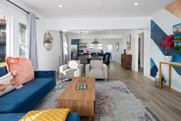 Un salon moderne avec un canapé bleu, une table basse en bois et un tapis à motifs.