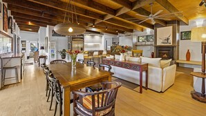 Amplia sala de estar con techo de madera, una mesa de comedor con sillas, un sofá y una chimenea.