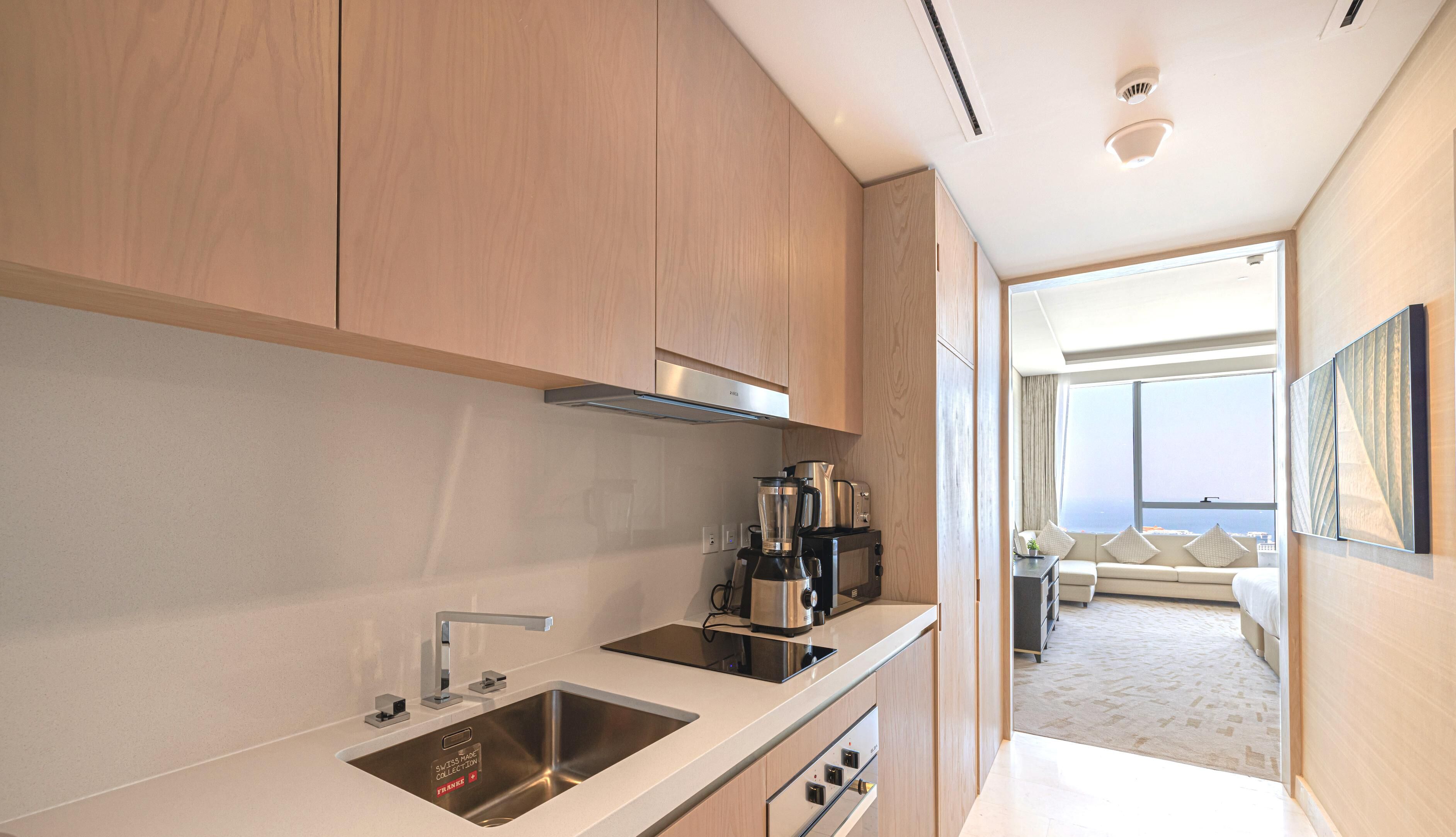 A modern kitchen with stainless steel appliances, a built-in oven, and a large window overlooking a balcony.