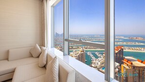 A modern living room with a large window offering a view of a marina and high-rise buildings. - Luxurious studio in St Regis Palm View (Dubai)