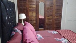 A bedroom with a bed, pillows, a lamp, and a wardrobe. - Brumalia Getaway in Mandeville Jamaica (Mandeville)