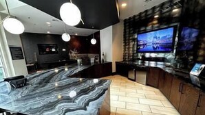 Een moderne keuken met een marmeren aanrecht, houten keukenkastjes en een grote flatscreen televisie.