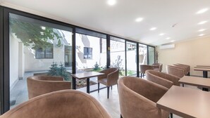 Uma área de refeições moderna com paredes de vidro, cadeiras marrons e mesas.