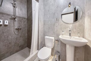 Een moderne badkamer met douche, toilet, wastafel en spiegel.