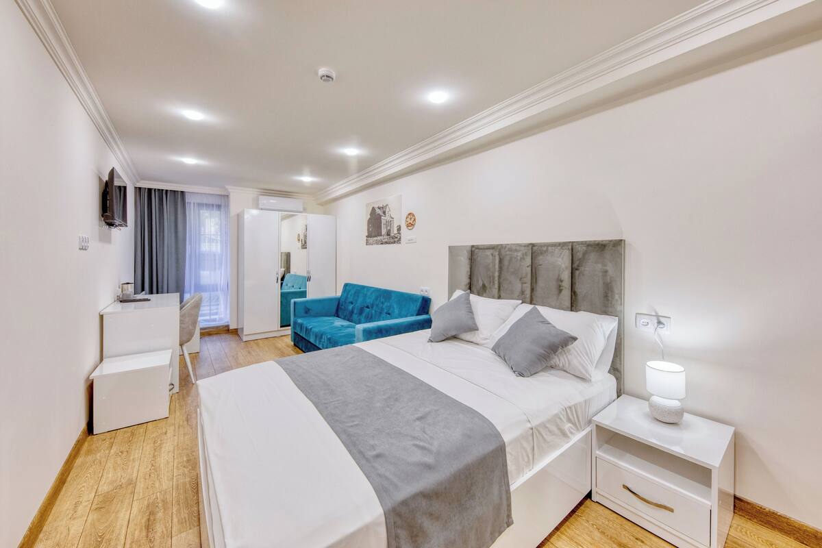 Un dormitorio moderno con cama, mesita de noche y escritorio con silla.