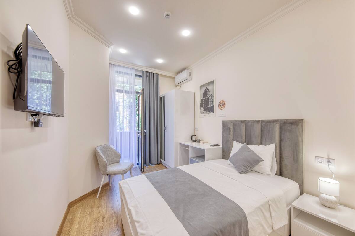 Una habitación de hotel moderna con una cama grande, un escritorio, una silla y un televisor.
