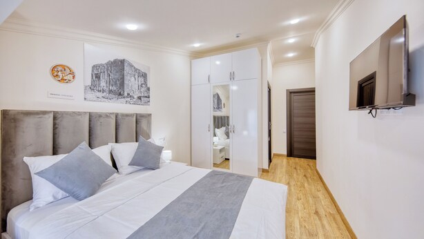 Quarto de hotel com cama, guarda-roupa, televisão e um quadro na parede.