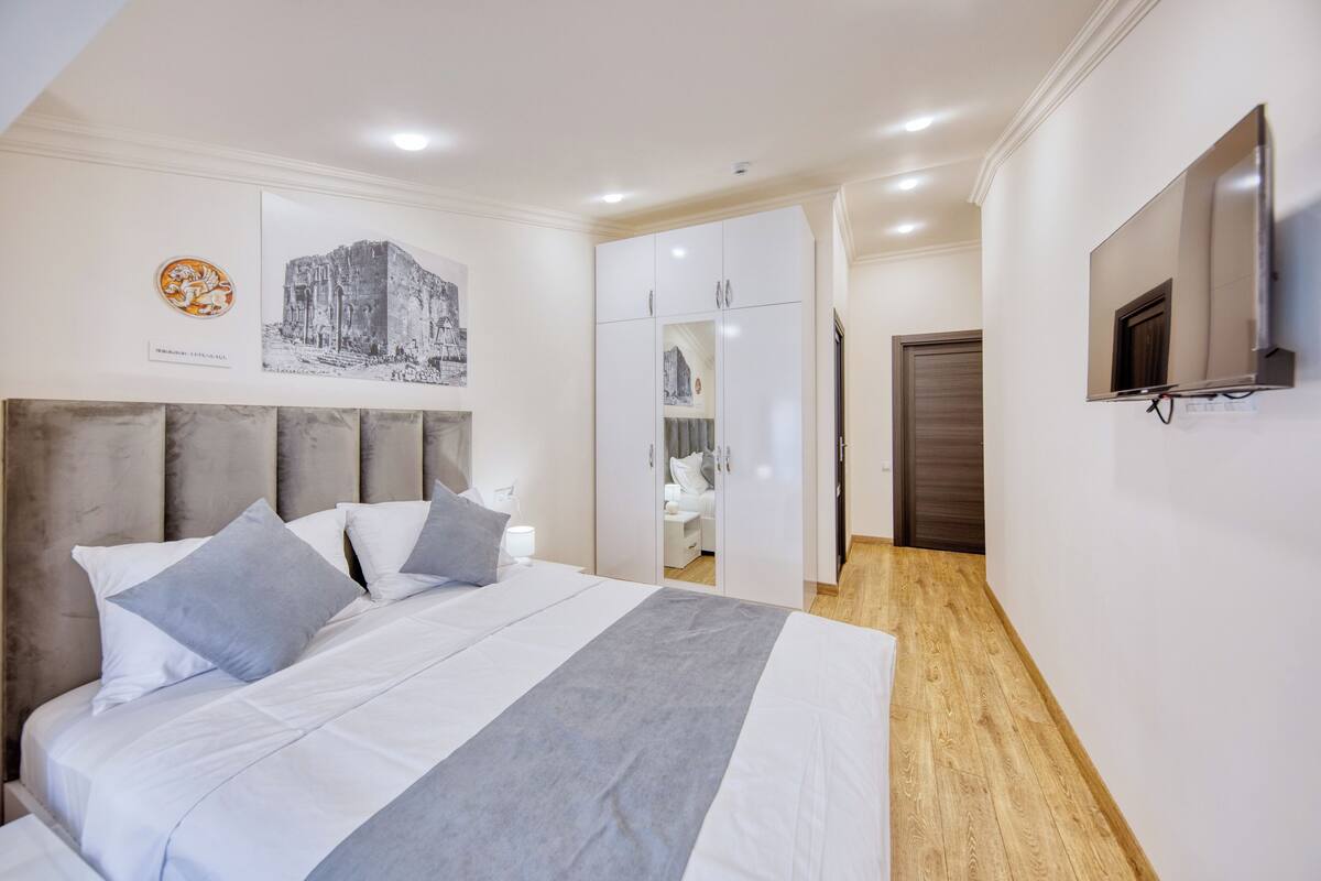Habitación de hotel con cama, armario, televisor y un cuadro en la pared.