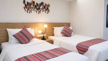 Habitación de hotel con dos camas, una mesita de noche con lámpara y un adorno en la pared.