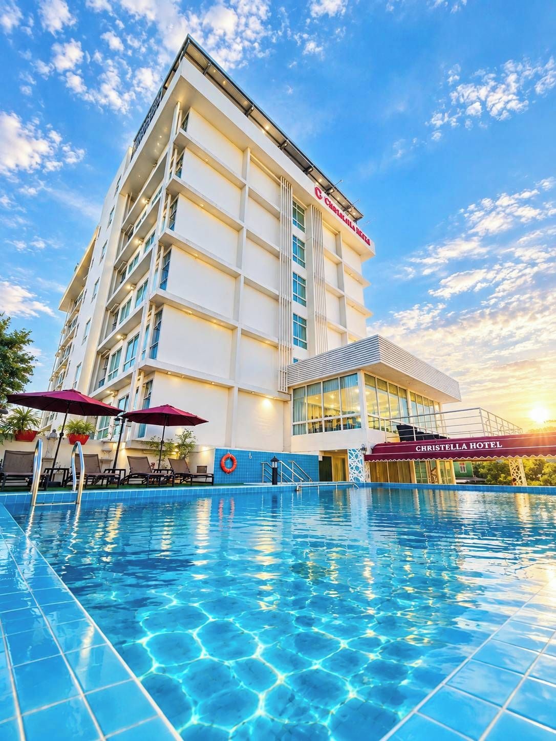 Un hotel con piscina, varios pisos y cielo despejado.