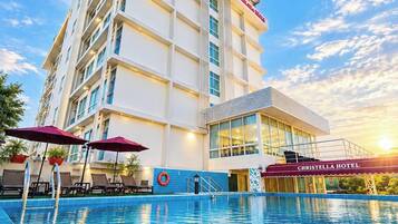 Un hotel con piscina, varios pisos y cielo despejado.