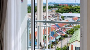 Un balcón con vistas a una zona residencial, un cartel de 'no estacionar' y un pájaro en la barandilla.