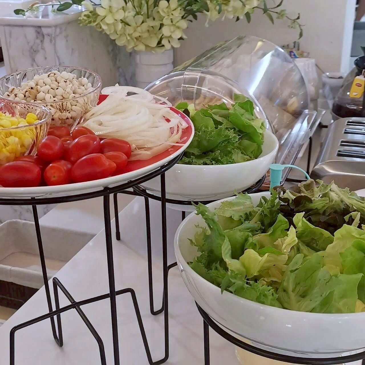 A buffet table with various food items including tomatoes, leafy greens, and other vegetables.