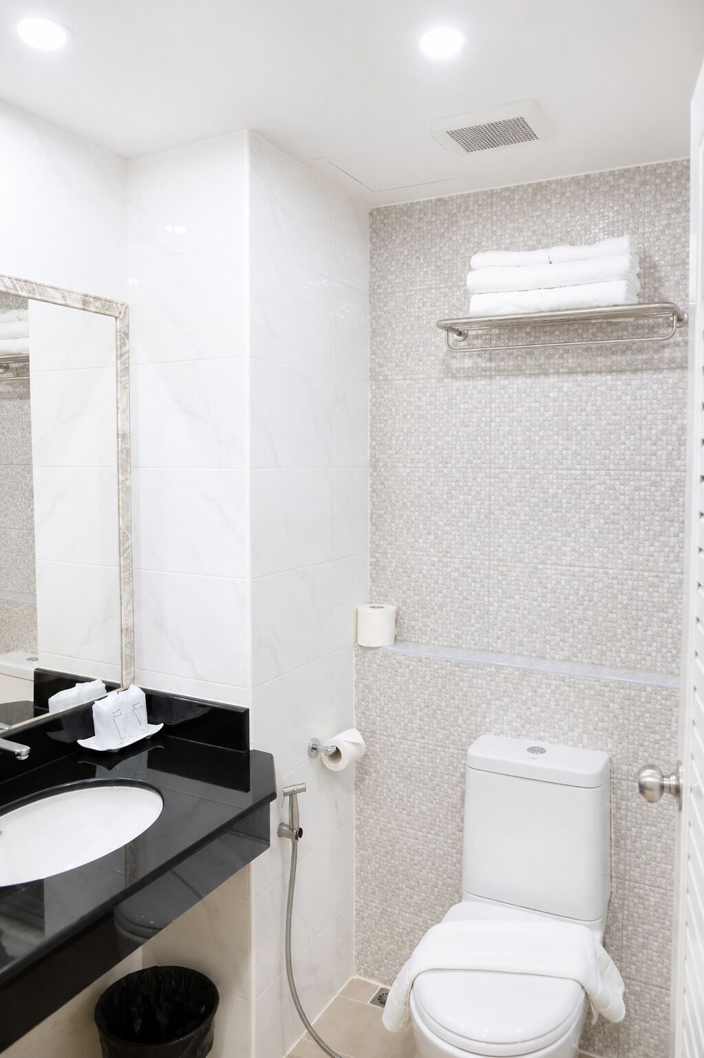 A bathroom with a white toilet, a black sink, a mirror, and a shower area.
