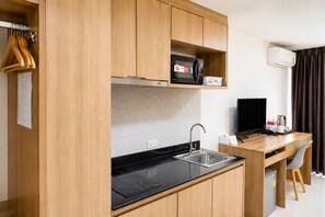 Eine kompakte Küchenzeile mit Spüle, Herd, Mikrowelle und kleinem Kühlschrank.
