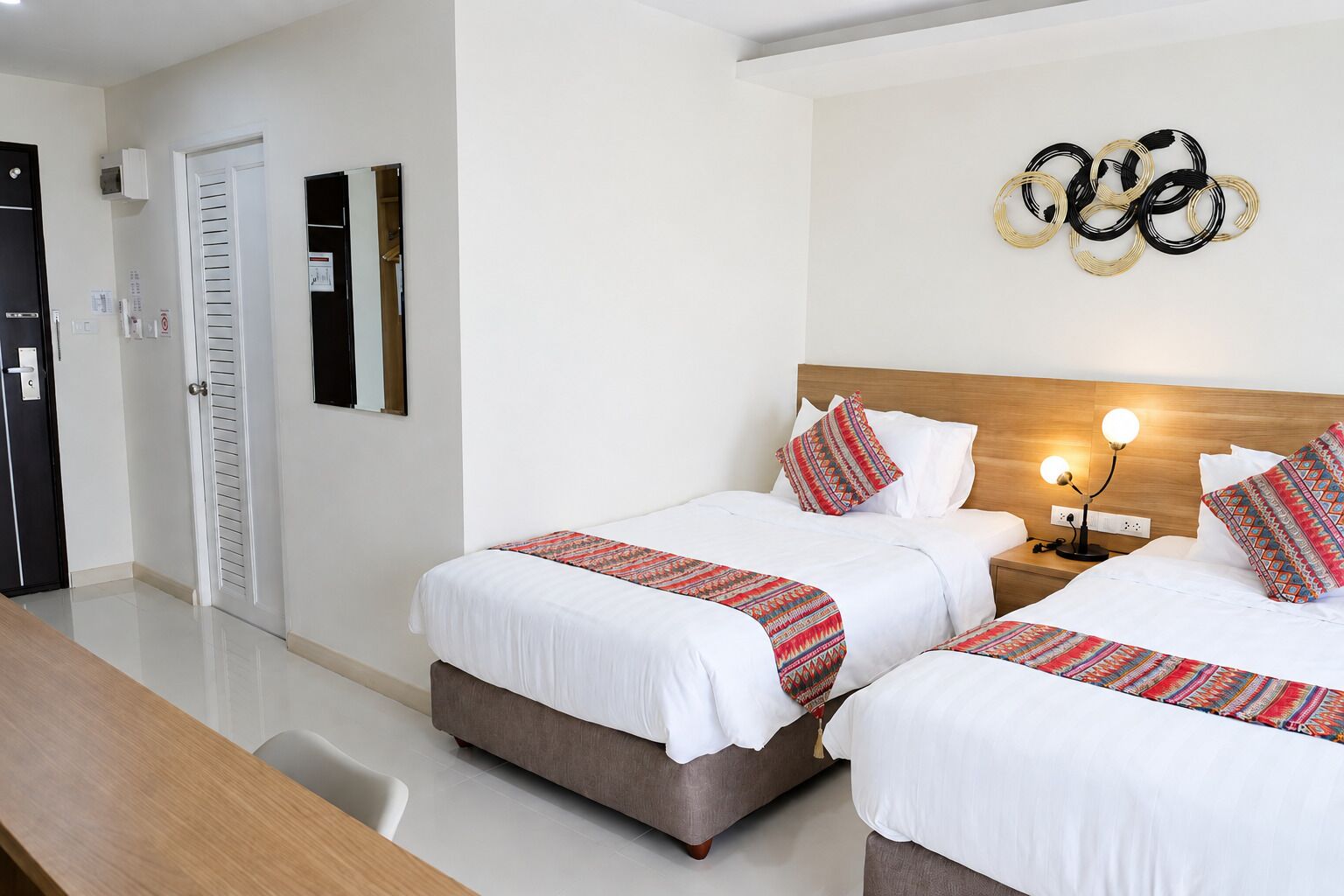 Habitación de hotel con dos camas, cabecero de madera, lámpara de pared y un espejo.