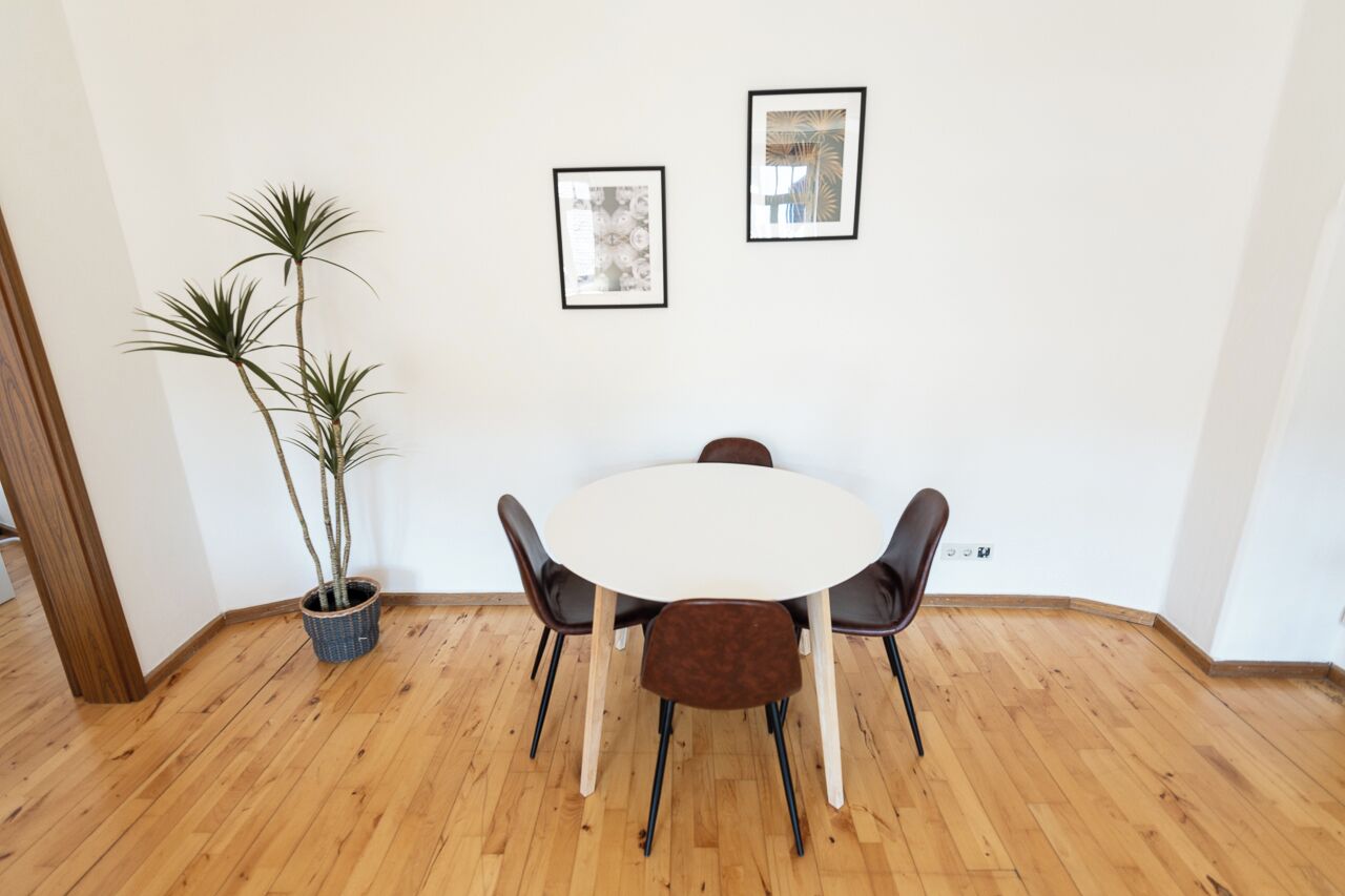 Et spiseområde med et rundt bord, fire stole og en potteplante.