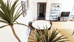 Una sala de estar moderna con una mesa de comedor redonda, un televisor y una planta.