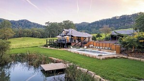 Una casa moderna con terraza, piscina y estanque.