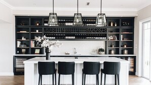A modern kitchen with a central island, black bar stools, and a wine rack.