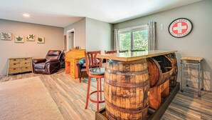 A room with a wooden barrel bar, leather chairs, a wooden dresser, and a ski patrol sign on the wall. - Wilmington Retreat Near Trails, Skiing & Festivals (Wilmington)