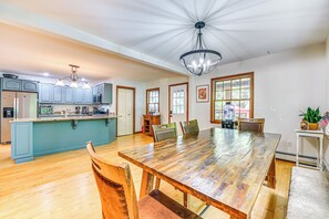 Uma cozinha espaçosa com uma ilha de madeira, uma sala de jantar com uma mesa grande e cadeiras, e um lustre.