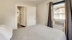 A bedroom with a bed, a door, and a window with curtains. - Hackensack Escape w/ Yard - 17 Mi to Times Square! (Hackensack)