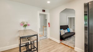 A modern living room with a sofa, a dining table with chairs, and a kitchen area with a refrigerator. - Hackensack Escape w/ Yard - 17 Mi to Times Square! (Hackensack)
