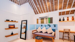 Un interior moderno con techo de madera, un sofá con cojines, un taburete de madera y estanterías con objetos decorativos.